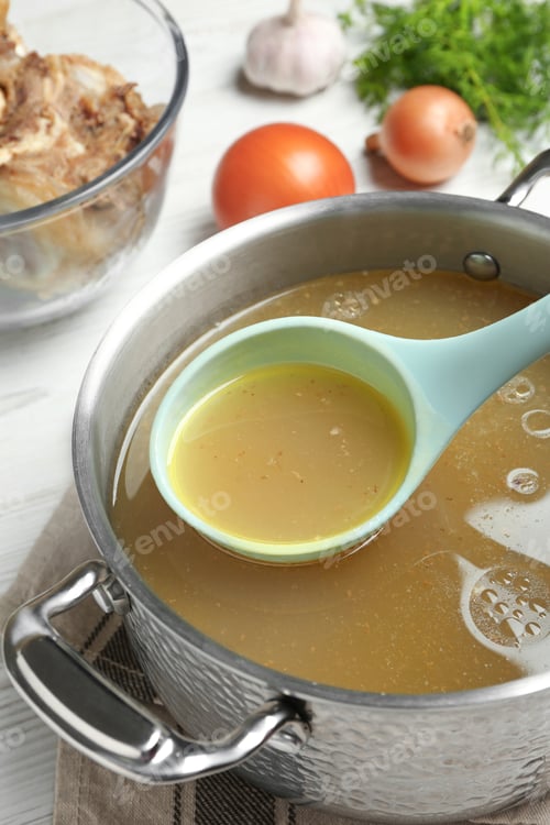 Preview: Delicious homemade bone broth and ingredients on white wooden table