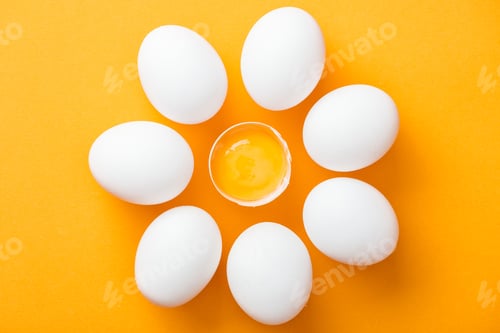 Preview: top view of whole white eggs and smashed one with yolk on bright orange background