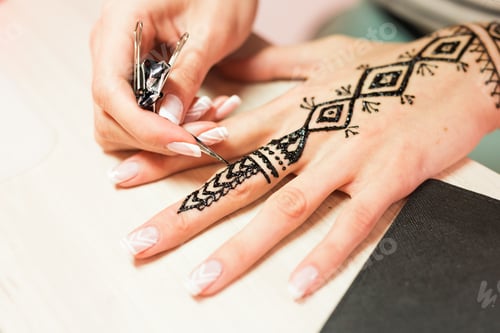Preview: young woman mehendi artist painting henna on the hand