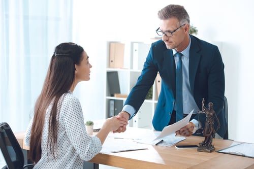 Preview: professional lawyer and young female client shaking hands in office