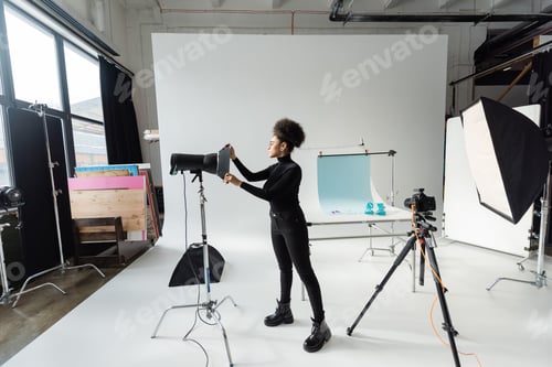 Preview: full length of african american content producer assembling lighting equipment in modern and