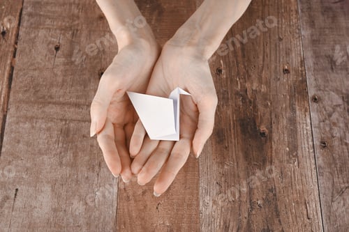 Preview: hands of an elderly woman fold origami paper. Creating an origami paper crane