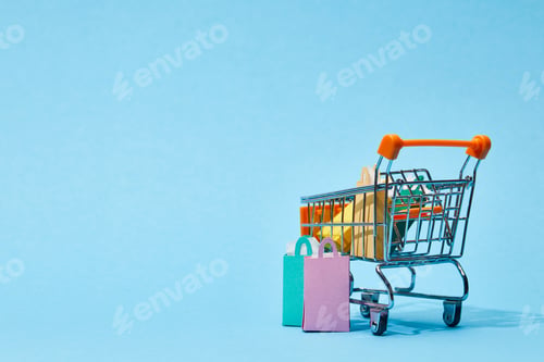 Preview: few small paper bags near toy cart with colorful shopping bags on blue