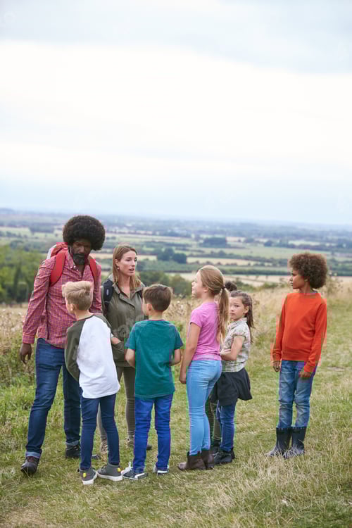 Preview: Adult Team Leaders With Group Of Children At Outdoor Activity Camp Walking Through Countryside