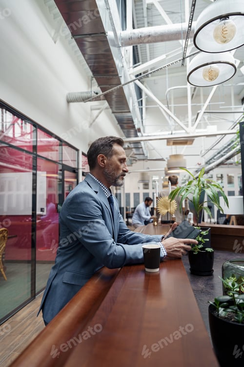 Preview: Handsome businessman standing in office during break and use phone