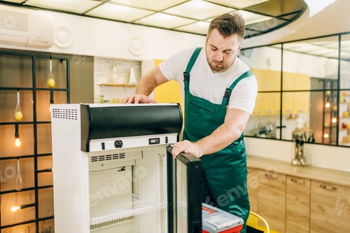Preview: Worker with toolbox repair refrigerator at home