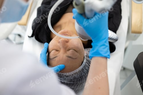 Preview: Face skin care. Asian woman getting facial laser treatment in clinic.