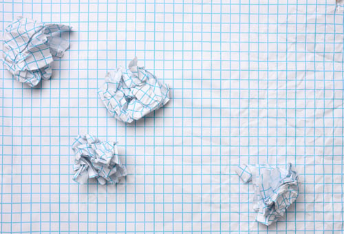 Preview: Blank crumpled white sheet of paper in a cage and crumpled balls, top view