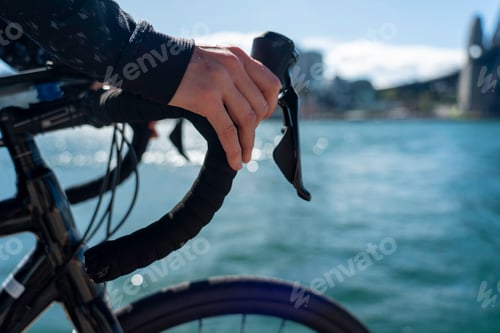 Preview: close up of hands on handle bar of road bike, ocean views in background, overlooking the harbour