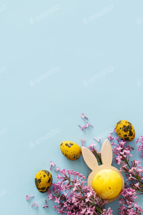 Preview: Happy Easter! Modern yellow eggs, bunny ears and lilac blossom flat lay with space for text