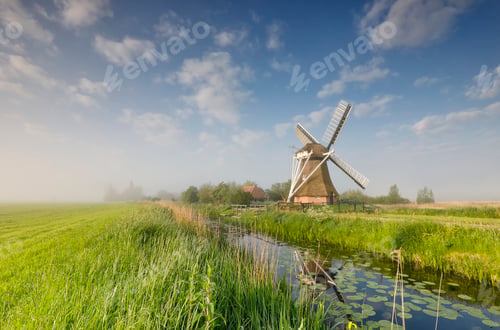 Preview: windmill on green meadow by river