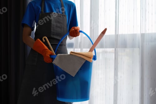 Preview: The cleaning lady wears orange rubber gloves and carries a bucket of bedroom cleaning supplies.