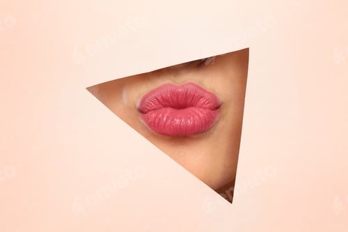 Preview: Young woman wearing beautiful lipstick, view through hole in color paper