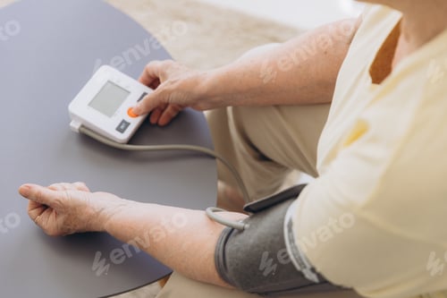 Preview: Close-up senior woman with hypertension measuring blood pressure herself at home.