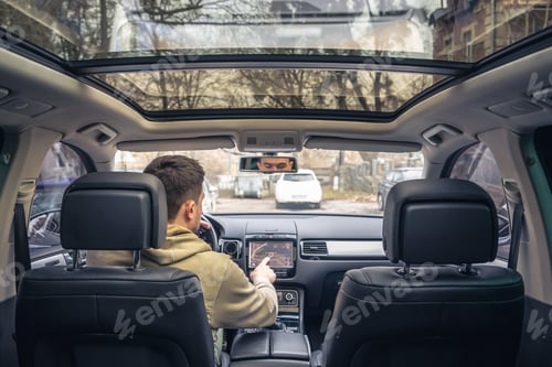 Preview: Man touching screen of a GPS navigation system in his car.