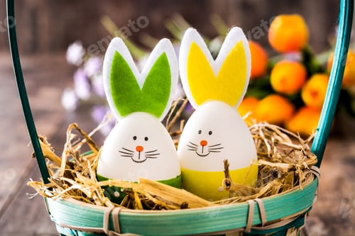 Preview: Easter eggs shaped like bunnies in basket with straw