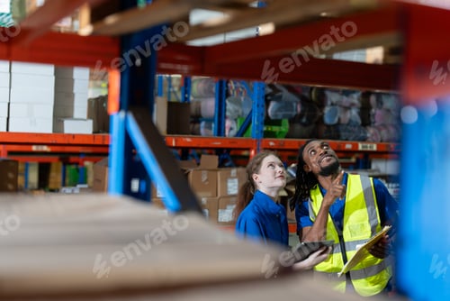 Preview: Female and man warehouse worker with tablet checking stock products on shelves at warehouse store