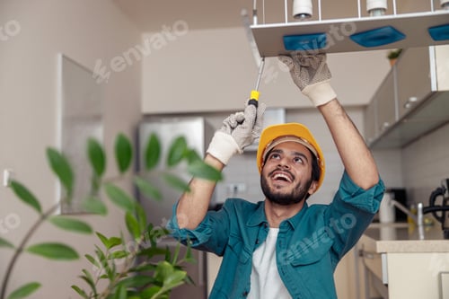 Preview: Professional electrician worker in uniform is installing electric lamps light in kitchen