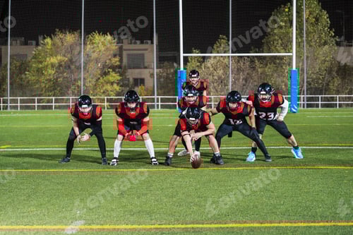 Preview: American football players lining up on field at night