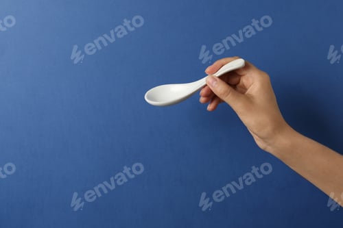 Preview: Woman holding empty miso soup spoon on color background, closeup. Space for text