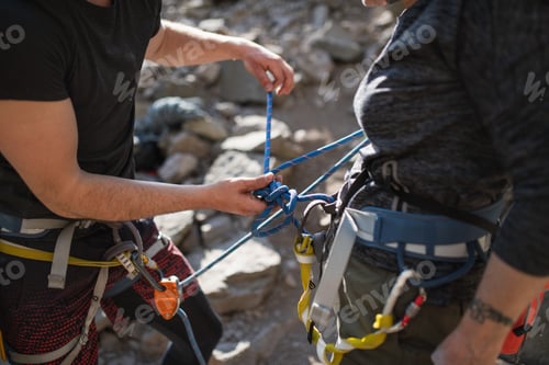 Preview: Instructor with senior woman getting ready for climbing rocks outdoors in nature, active lifestyle.