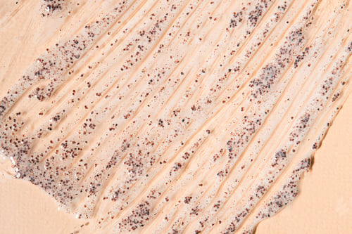 Preview: A smear of coffee scrub on a beige background with copy space.