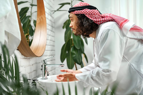 Preview: Young Arab man getting ready and looking at the mirror in the bathroom