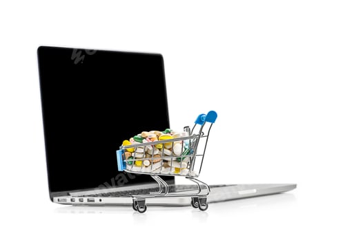 Preview: Shopping cart with different tablets near notebook. Purchase of drugs and medicine online.