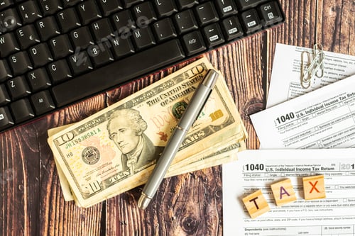 Preview: Dollar bills on a table in which the 1040 American tax payment form is filled out.