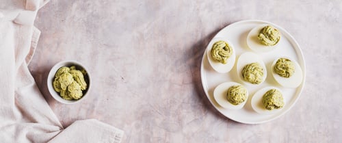 Preview: Avocado deviled eggs for appetizer on plate on table top view web banner