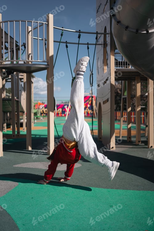Preview: Child girl doing handstand on the outdoors playground. Funny active exercise