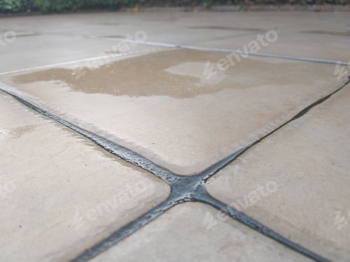 Preview: High angle shot of a tiled ground with a wet part on some of it
