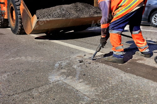 Preview: A worker clears a piece of asphalt with a pneumatic jackhammer in road construction