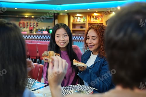 Preview: Friends eating pizza and enjoying time together in a restaurant