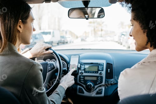 Preview: Two women driving in a car through the city using a telephone navigation app