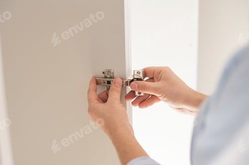Preview: Men's hands fasten the door hinge to the closet