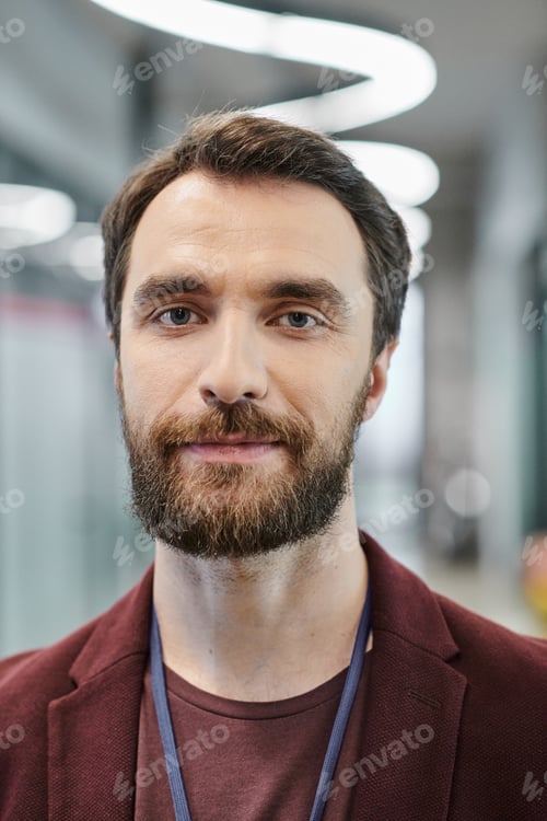 Preview: portrait of confident bearded entrepreneur looking at camera in modern coworking office