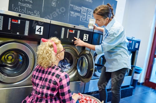 Preview: Laundrette business owner showing woman washing machine control panel