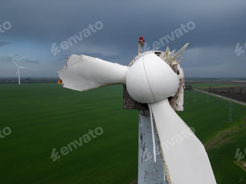 Preview: Close-up of a damaged wind turbine blade on a large green field with multiple turbines