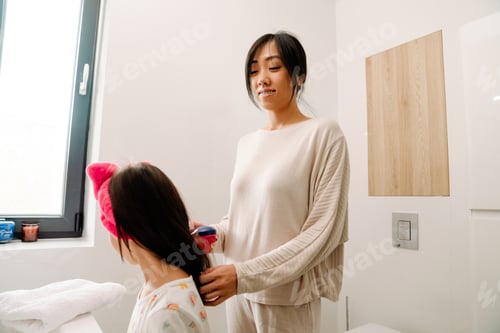 Preview: Woman Styling Child's Hair in Bright Bathroom