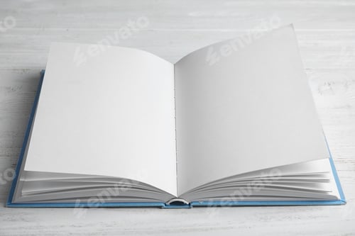 Preview: Open book on white wooden table. Space for text