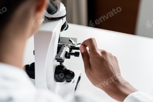 Preview: Cropped shot of professional chemist working with microscope in laboratory