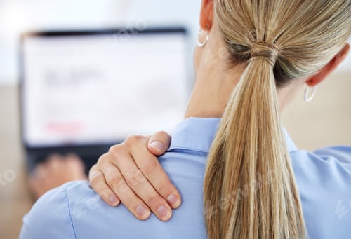 Preview: Young business woman rubbing neck in pain while working in office from behind