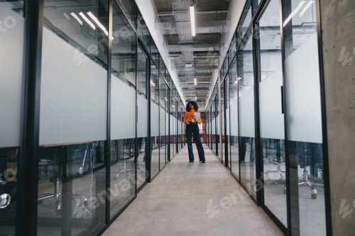 Preview: Confident Black businesswoman stands mid-corridor in an office