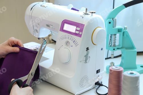 Preview: Seamstress profession. Young woman sews unique things for children on a sewing machine