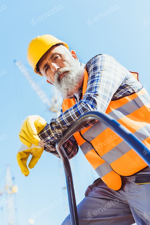 Preview: Bearded construction worker in reflective vest and hardhat leaning on guardrail