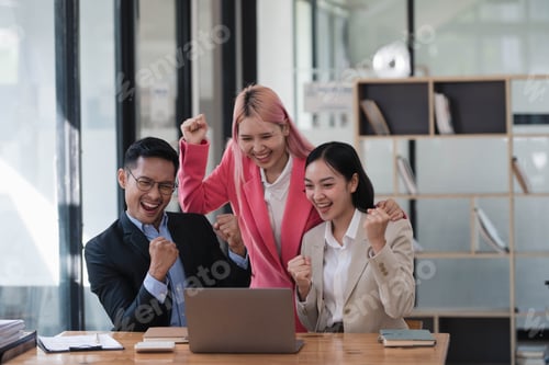 Preview: Excited happy business people celebrating together after hearing the good news