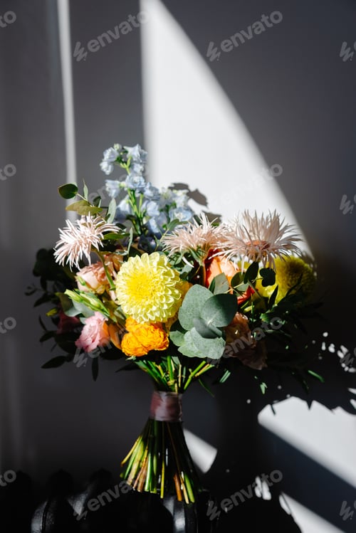 Preview: Colorful bridal bouquet resting on a chair, illuminated by window light