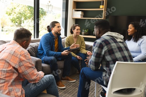 Preview: Diverse group of friends and male therapist with tablet in group therapy session