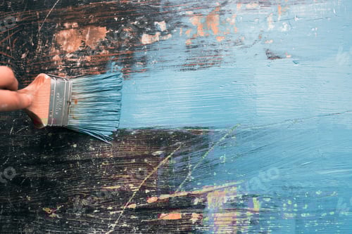 Preview: Close up paintbrush in hand and painting on the wooden table.